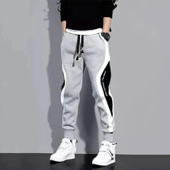 Men's grey ankle-length joggers featuring black and white side panels and an elastic drawstring.