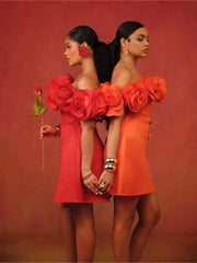 Two models stand back-to-back wearing mini dresses with large 3D floral appliques at the neckline.