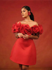 A woman wears a red off-the-shoulder mini dress featuring large three-dimensional rose appliques.