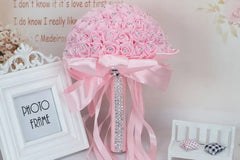 A round bridal bouquet of pink foam roses accented with rhinestones and a satin ribbon handle.