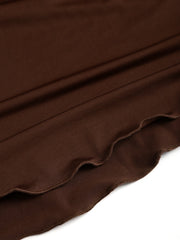 A close-up view of the brown fabric and wavy lettuce-edge hem of a long-sleeve dress.