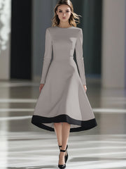 A woman wears a long-sleeved, light gray midi dress with a black hem and a cinched waist.