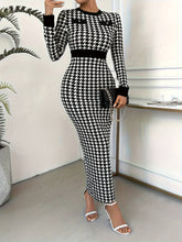A woman wears a long-sleeved, bodycon houndstooth dress with a crew neck and black trim.