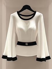 A white long-sleeve blouse with black trim on the round neckline, flared cuffs, and waist belt.