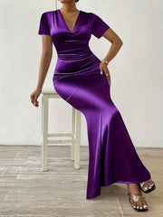 A woman wears a short-sleeved, floor-length purple satin bodycon dress with a V-neckline.
