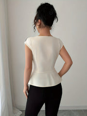 A woman wears a cream-colored sleeveless square-neck blouse with a peplum hem and black pants.