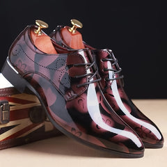 A pair of men's burgundy floral pattern faux leather oxford dress shoes with a pointed toe.