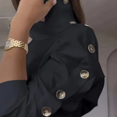 A black high-neck blouse featuring decorative silver buttons along the shoulder and sleeve.
