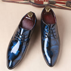 A pair of men's pointed-toe oxford dress shoes featuring a glossy blue floral pattern.