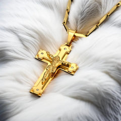 A gold-colored stainless steel crucifix pendant hangs from a matching link chain.