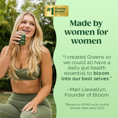 A woman in green athletic wear holds a glass of green superfood drink outdoors.