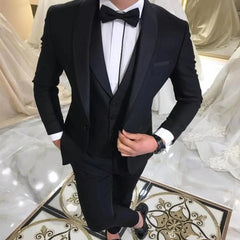 A man wears a black three-piece tuxedo with a shawl lapel, white shirt, and black bow tie.