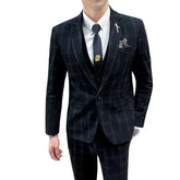 A man wears a dark plaid three-piece suit consisting of a blazer, vest, and matching trousers.