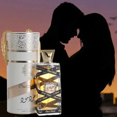 A bottle of Oud Mood perfume and its cylindrical white gift box against a sunset silhouette.