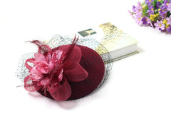 A burgundy vintage-style fascinator hat with a floral accent, feathers, and black netting.