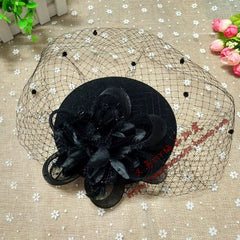 A black vintage-style fascinator hat featuring a decorative flower and a dotted mesh veil.