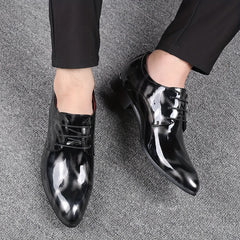A pair of men's black glossy pointed-toe oxford dress shoes with a subtle floral pattern.