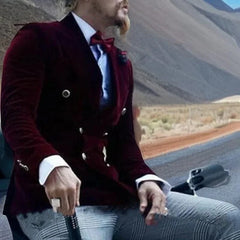 A man wears a burgundy velvet double-breasted blazer with a white shirt and patterned trousers.