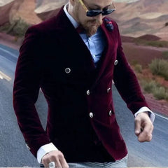 A man wears a slim-fit, double-breasted burgundy velvet blazer with silver buttons.