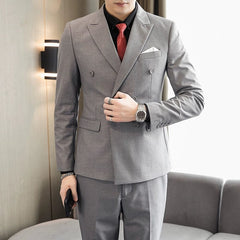 A man wears a grey double-breasted business suit with a black shirt and red tie.