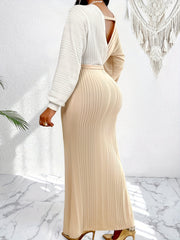 A woman wears a long-sleeved, two-tone bodycon dress with a white top and beige pleated skirt.