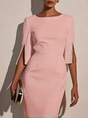 Women's elegant pink dress with split sleeves adorned with pearls and a gold clutch.