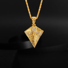 A gold-toned, diamond-encrusted crucifix pendant hangs from a matching chain against a black background.