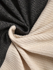 A close-up view of a soft, ribbed knit fabric featuring a color-block design in charcoal and beige.