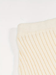 A close-up of a cream-colored, ribbed knit skirt featuring a high-waisted design.