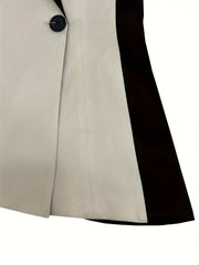 A close-up of a two-tone asymmetrical blazer featuring a single black button and color-block design.