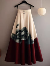 A beige and red A-line midi skirt featuring a floral print and two front buttons.