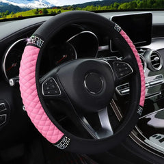 A pink and black quilted faux leather steering wheel cover with rhinestone accents.