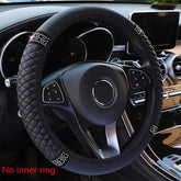 A black quilted faux leather steering wheel cover with diamond-encrusted accents.