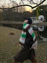 A woman wears a long, fuzzy, multicolored striped mohair scarf with fringe tassels.