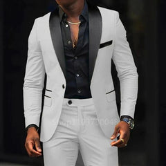 A man wears a white slim-fit two-piece suit with a black shawl lapel and a black button-down shirt.