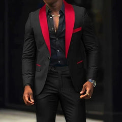 A man wears a black slim-fit suit featuring a red shawl lapel and matching red pocket accents.