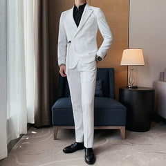 A man wears a slim-fit white suit jacket with a side buckle and matching white trousers.