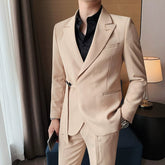 A man wears a slim-fit beige suit jacket featuring a side buckle closure and a black shirt.