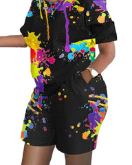 A woman wears a black short-sleeve t-shirt and shorts set featuring a colorful paint splatter print.