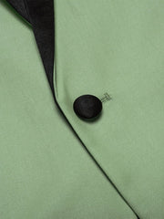 A close-up of a light green men's suit jacket featuring a black satin shawl collar and button.
