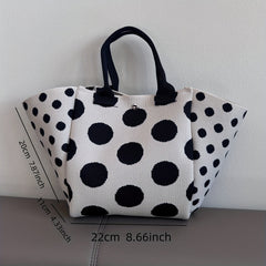 A white and black polka dot knit tote bag with black handles and a magnetic closure.