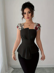 A woman wears a black square-neck peplum blouse featuring sheer floral-embroidered cap sleeves.