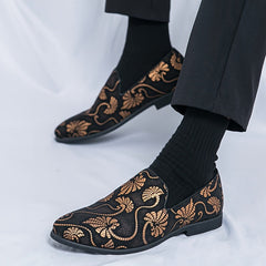 Men's black slip-on shoes featuring a gold floral embroidery pattern and a rubber sole.