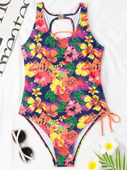 A one-piece swimsuit featuring a vibrant tropical floral print and a lace-up side detail.