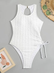 A white one-piece swimsuit with a textured fabric, high-cut legs, and a side tie detail.