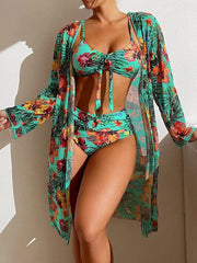 A woman wears a green floral three-piece bikini set with a matching long-sleeved mesh cover-up.