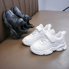 A pair of white and a pair of black children's sneakers with hook and loop closures.