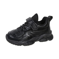 A black children's sneaker with a hook and loop strap and a chunky rubber sole.