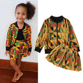 A young girl wears a patterned jacket and skirt set featuring a colorful geometric print.