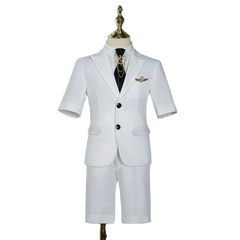 A white short-sleeved children's suit with a black tie and gold lapel pin on a mannequin.